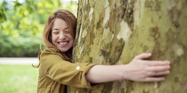 Frau umarmt großen, dicken Baum